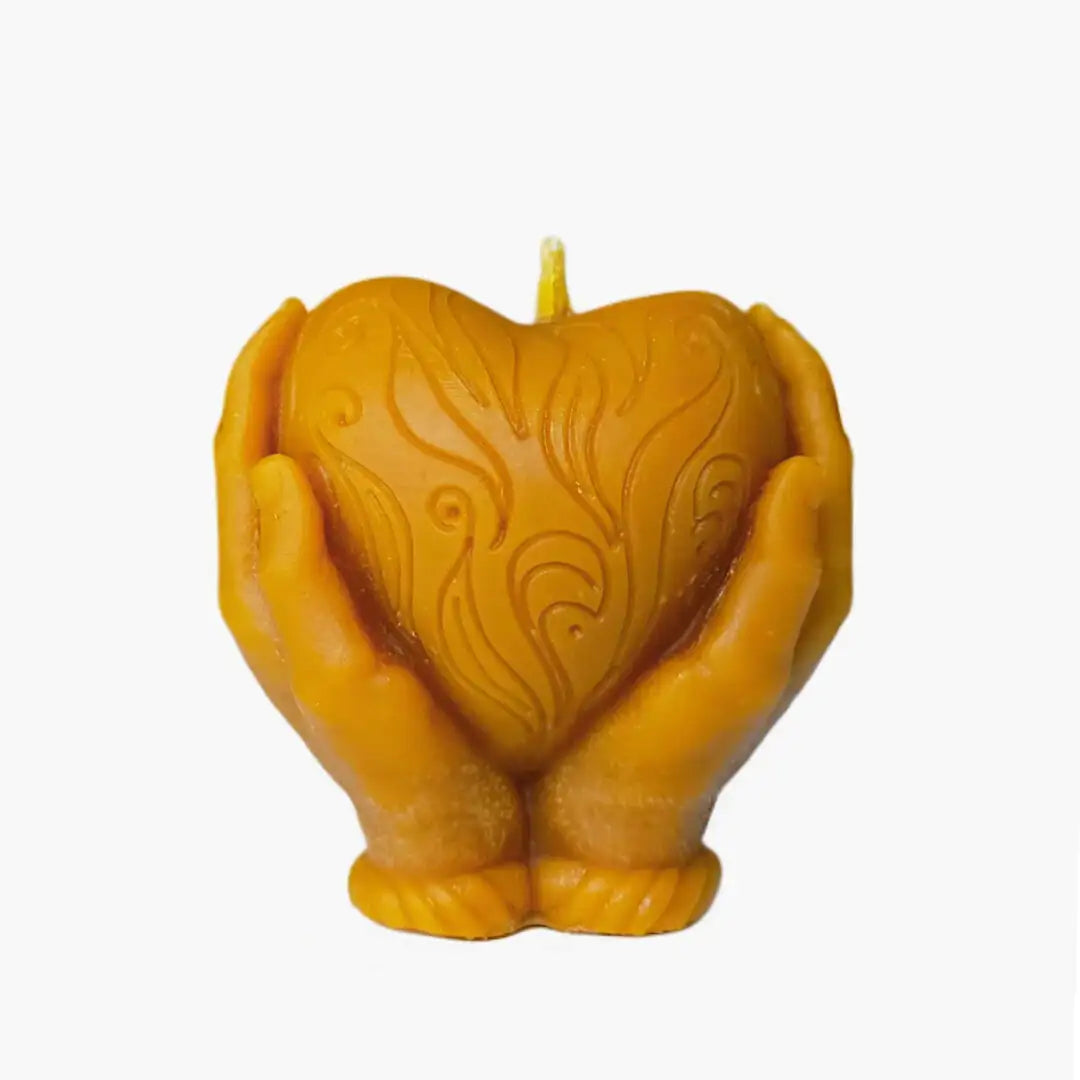 Vela artesanal de cera de abeja en forma de manos sosteniendo un corazón, color amarillo natural, sobre fondo blanco