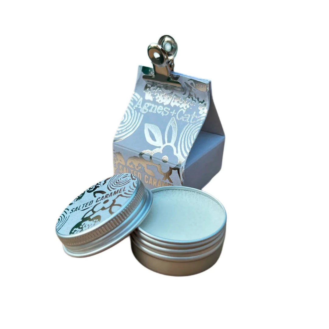 Bálsamo labial natural de caramelo salado en envase metálico redondo con caja de diseño artesanal. Hidratación vegana con aroma dulce y salado.