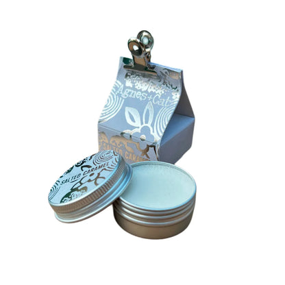Bálsamo labial natural de caramelo salado en envase metálico redondo con caja de diseño artesanal. Hidratación vegana con aroma dulce y salado.