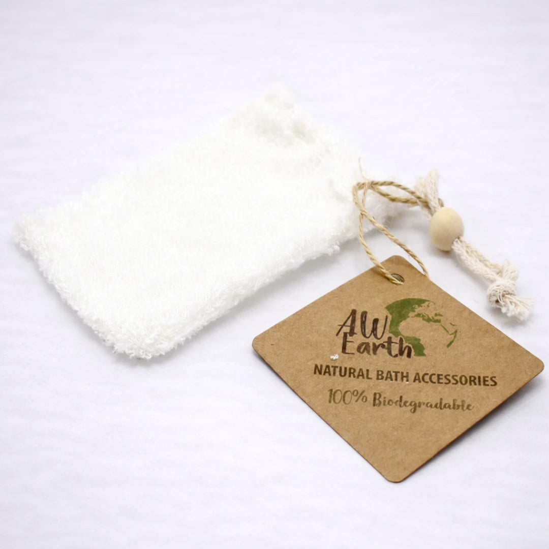 Bolsa exfoliante de bambú biodegradable con cordón y etiqueta ecológica sobre fondo grisáceo suave