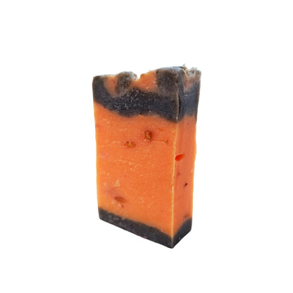 Jabón artesanal de canela y naranja de pie, elaborado a mano, con vetas oscuras y tono anaranjado, ideal para exfoliar e hidratar la piel