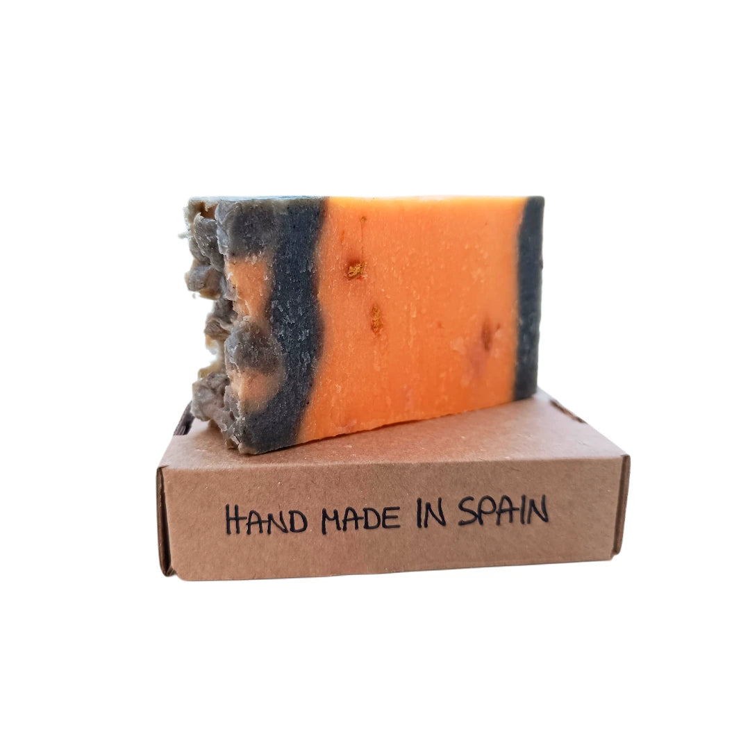 Pastilla de jabón artesanal de canela y naranja sobre caja de cartón con la inscripción "Hand Made in Spain", producto natural hecho a mano.