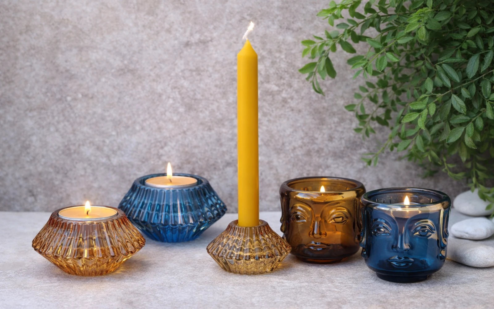 Portavelas de cristal azul y ámbar con velas encendidas en ambiente relajante y elegante