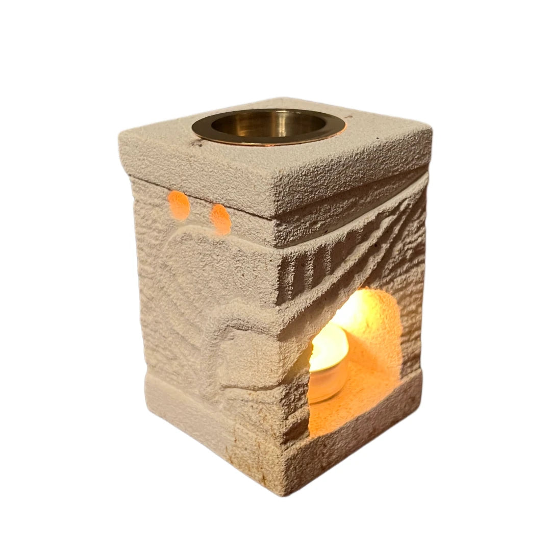 Quemador de aceites esenciales de piedra natural con vela encendida para aromaterapia.