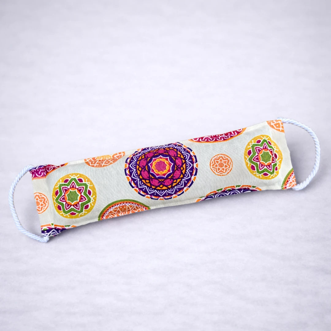 Saco térmico natural con estampado de mandalas multicolor, ideal para relajación y alivio muscular, presentado sobre fondo gris suave.