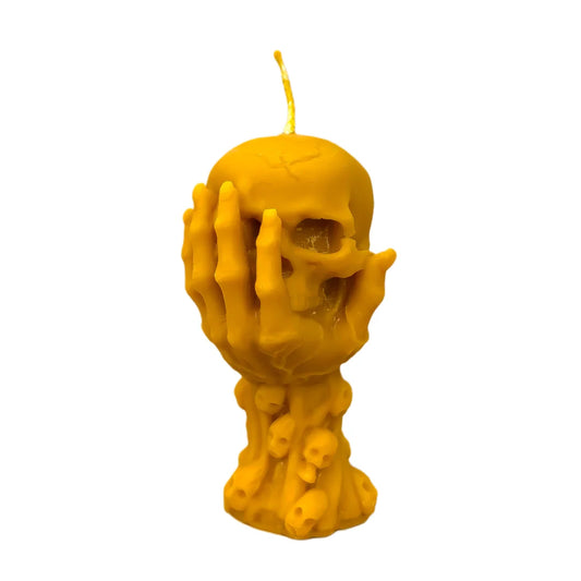 Vela Silencio Eterno con mano sosteniendo una calavera hecha de cera de abeja 100% natural sobre fondo blanco