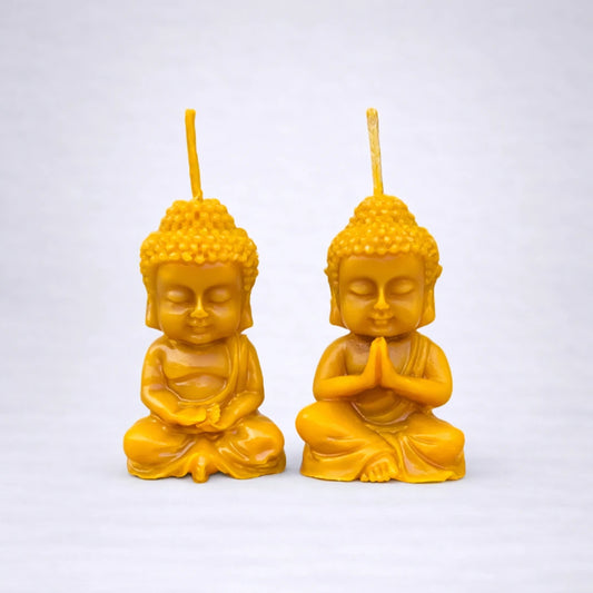 Velas de cera de abeja en forma de budas sentados, símbolo de calma y serenidad, sobre fondo gris suave