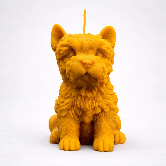 Vela artesanal de cera de abeja con forma de yorkshire terrier sobre fondo gris suave