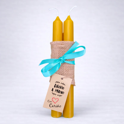 Pack de velas pilar de cera de abeja natural atadas con cinta y etiqueta hecho a mano, presentación artesanal sobre fondo gris neutro