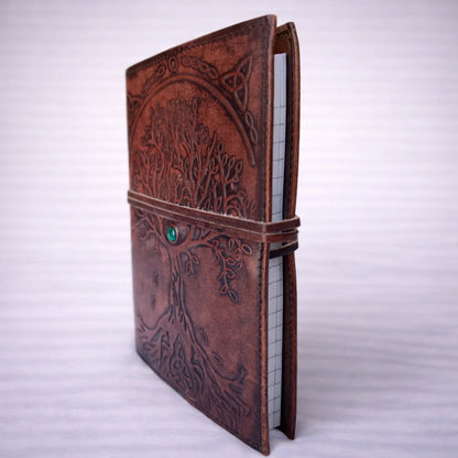 Cuaderno de cuero artesanal con Árbol de la Vida grabado, vista lateral con páginas interiores y acabado envejecido