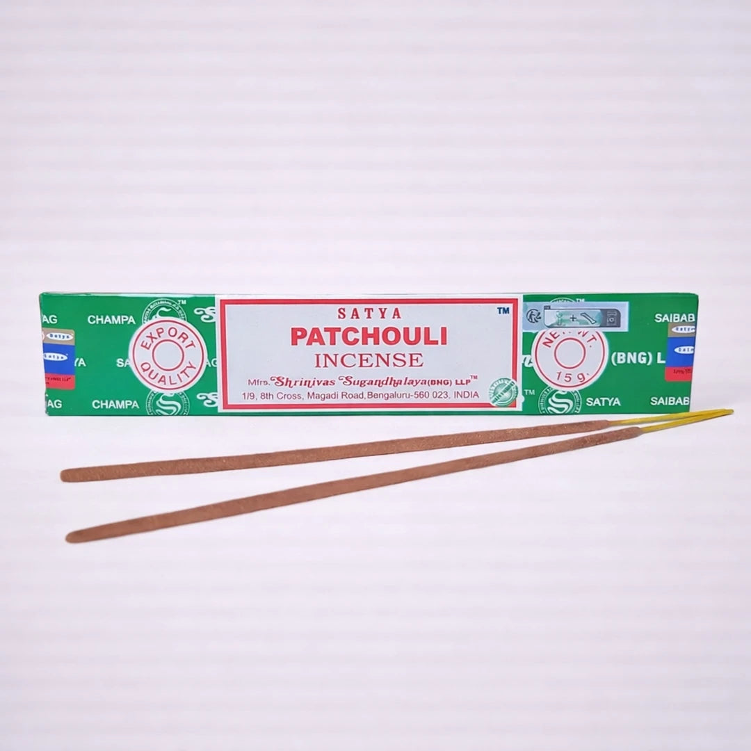 Incienso Satya Patchouli natural con varillas artesanales sobre fondo grisáceo suave, aroma intenso y terroso ideal para relajación y meditación