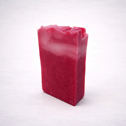 Jabón artesanal de karité rosa hecho a mano en España, pastilla natural hidratante con acabado rústico sobre fondo gris claro