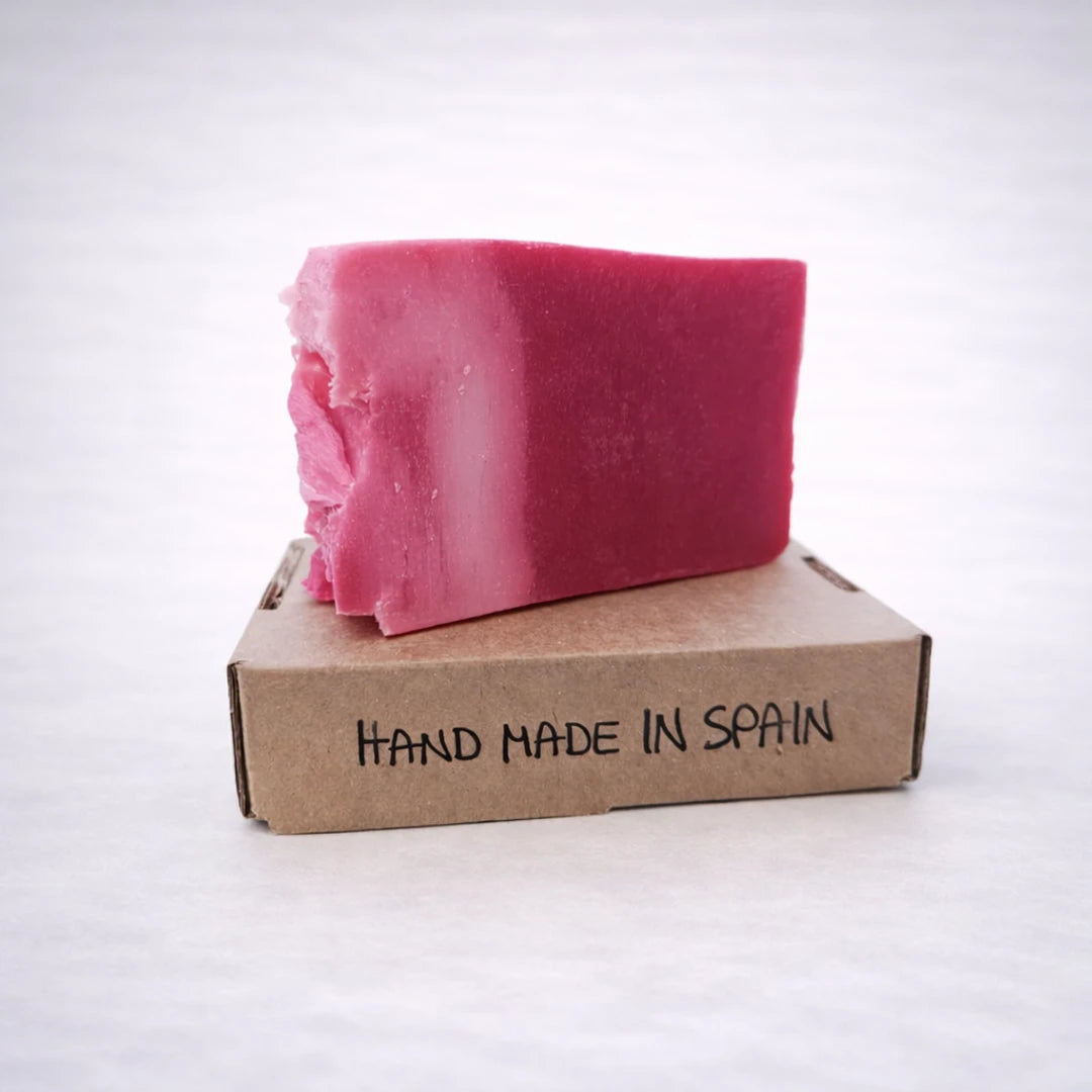 Jabón natural de karité rosa colocado sobre caja kraft hecha a mano en España, cosmética artesanal con fondo gris claro