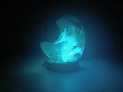 Lámpara de sal del Himalaya luna encendida con luz RGB azul, ideal para crear ambientes relajantes y purificar el aire.