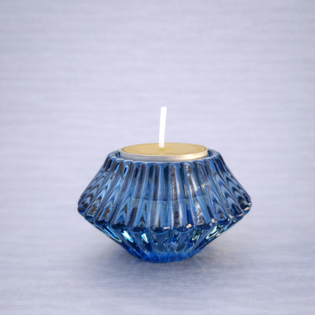 Portavelas reversible azul de vidrio con vela tipo tea light sobre fondo neutro