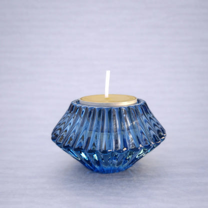 Portavelas reversible azul de vidrio con vela tipo tea light sobre fondo neutro