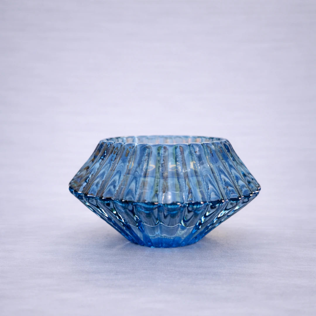 Portavelas reversible de cristal azul con acabado acanalado sobre fondo gris suave