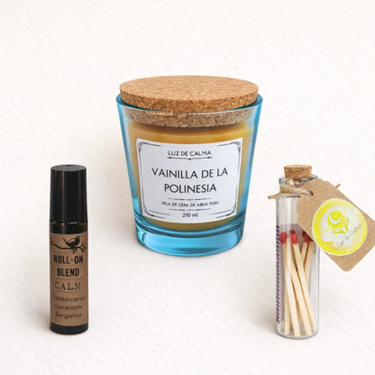 Pack de bienestar Luz de Calma con vela aromática de vainilla en vaso turquesa, roll-on Calm y cerillero artesanal sobre fondo claro.
