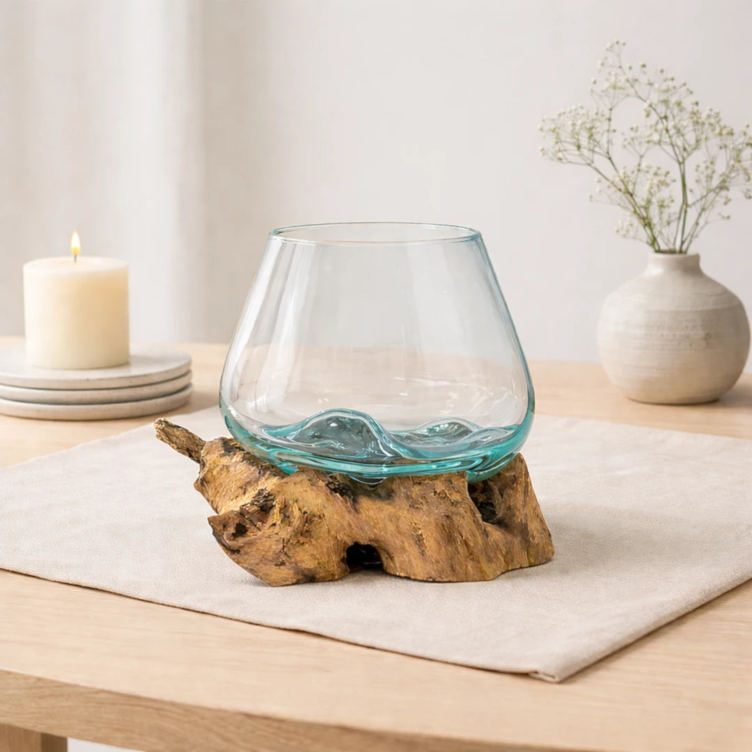 Cuenco de vidrio fundido sobre madera natural en una escena minimalista con vela y flores secas