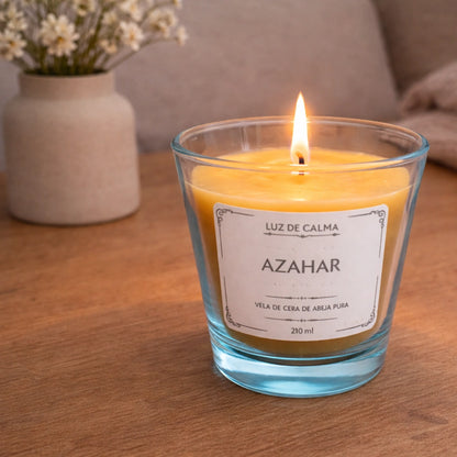 Vela aromática de cera de abeja con fragancia azahar encendida sobre mesa de madera, creando un ambiente cálido, acogedor y relajante en el hogar