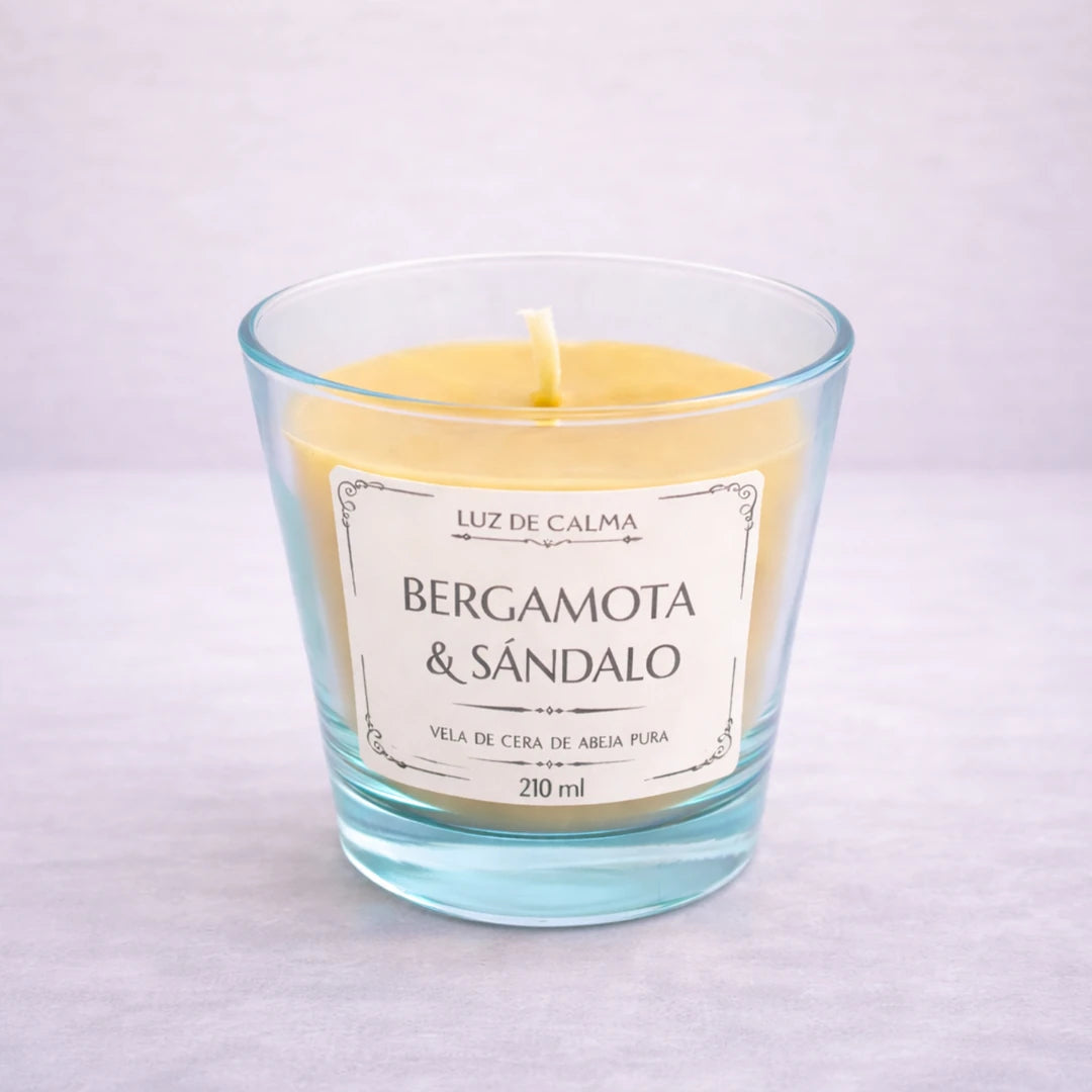 Vela artesanal de cera de abeja con aroma bergamota y sándalo en vaso de vidrio elegante, creando un ambiente sofisticado y relajante