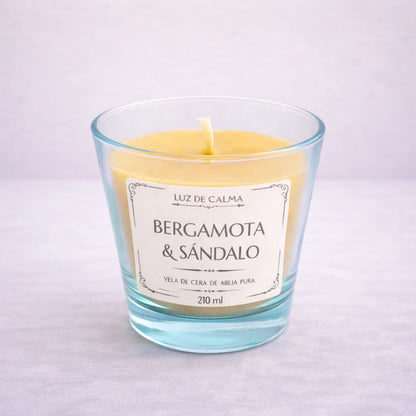 Vela artesanal de cera de abeja con aroma bergamota y sándalo en vaso de vidrio elegante, creando un ambiente sofisticado y relajante