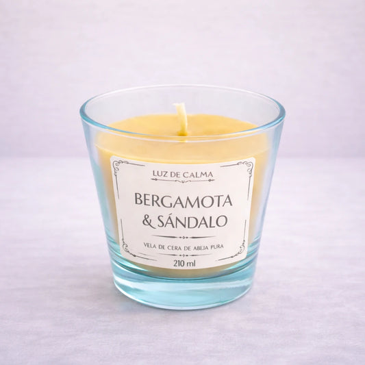 Vela artesanal de cera de abeja con aroma bergamota y sándalo en vaso de vidrio elegante, creando un ambiente sofisticado y relajante
