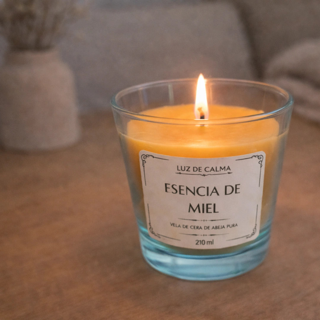 Vela de cera de abeja Esencia de Miel encendida sobre mesa de madera, creando un ambiente acogedor, relajante y lleno de calidez