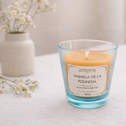Vela aromática de cera de abeja Vainilla de la Polinesia en ambiente minimalista con flores, transmitiendo calma, dulzura y un aroma cálido y envolvente
