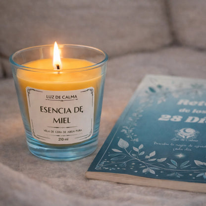 Vela perfumada Esencia de Miel encendida junto a un libro, creando un ambiente relajante, íntimo y perfecto para momentos de descanso en casa