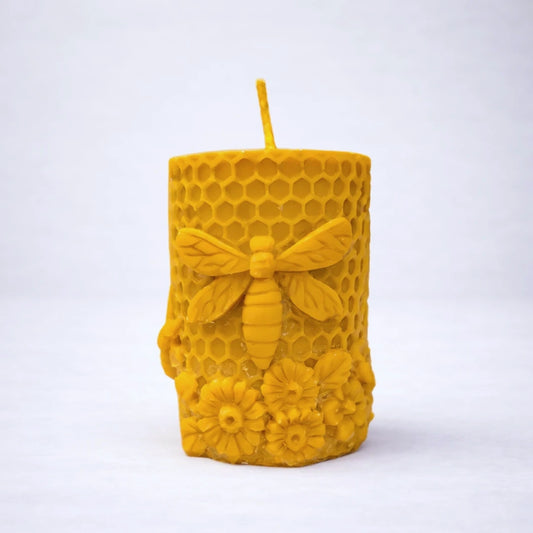 Vela artesanal de cera de abeja con diseño de panal, abeja y flores, elaborada en cera natural.